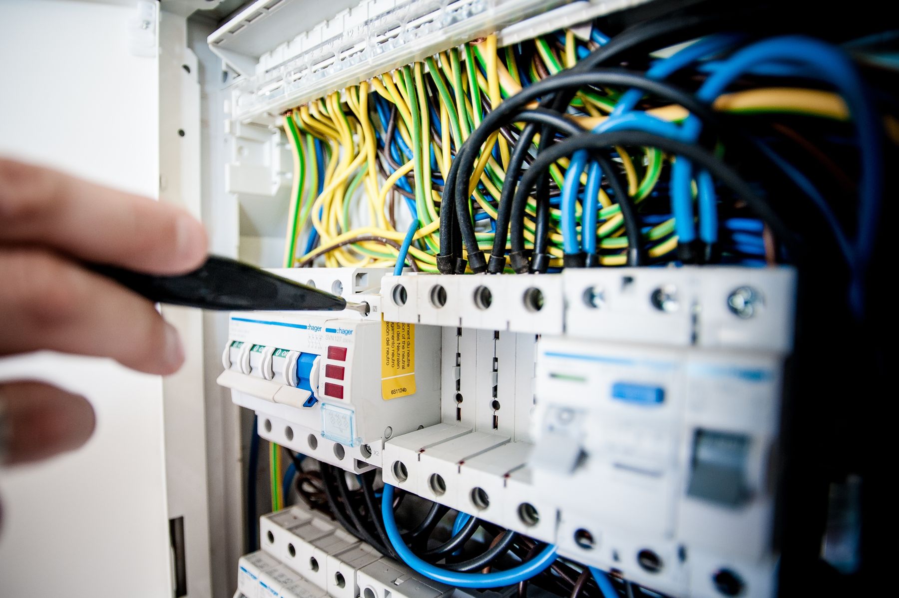 Electrician's hand working on an open switchboard