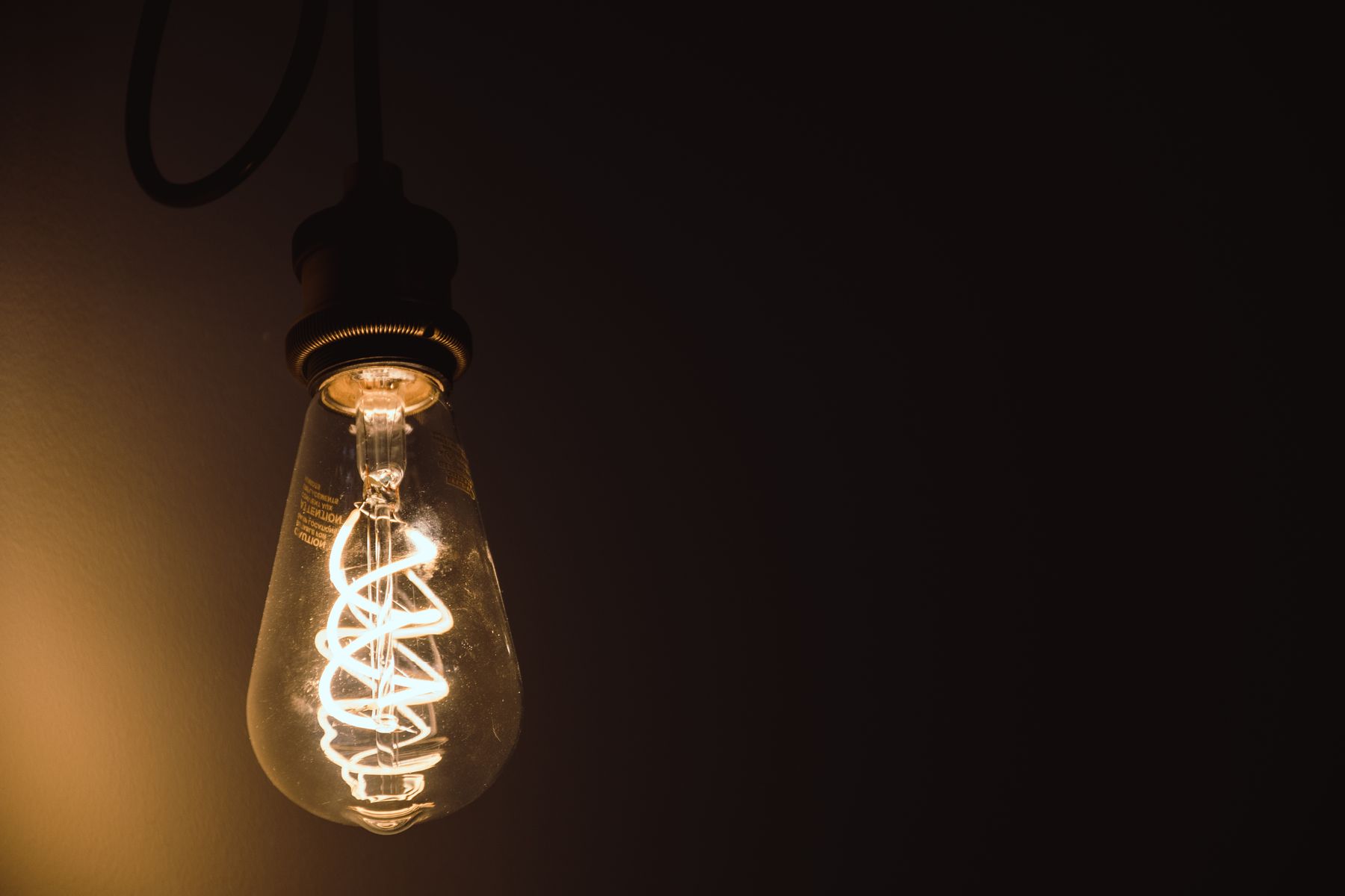 Glowing filament light bulb against a dark background